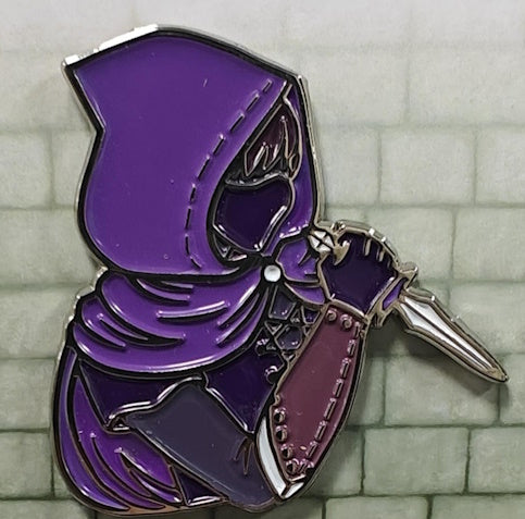A 1.5 inch enamel pin featuring a stylized purple rogue character with a purple cloak and dagger.