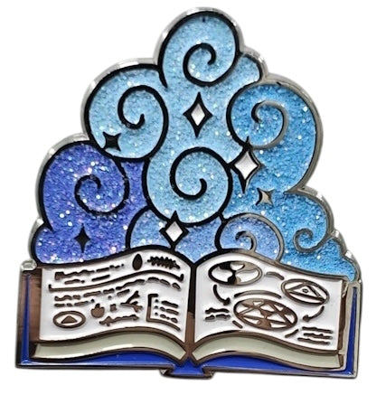 A 1.5 inch enamel pin with a blue and white design featuring a stylized book and magical symbols, representing the Wizard character class.