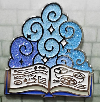 A 1.5 inch enamel pin with a blue and white design featuring a stylized book and magical symbols, representing the Wizard character class.