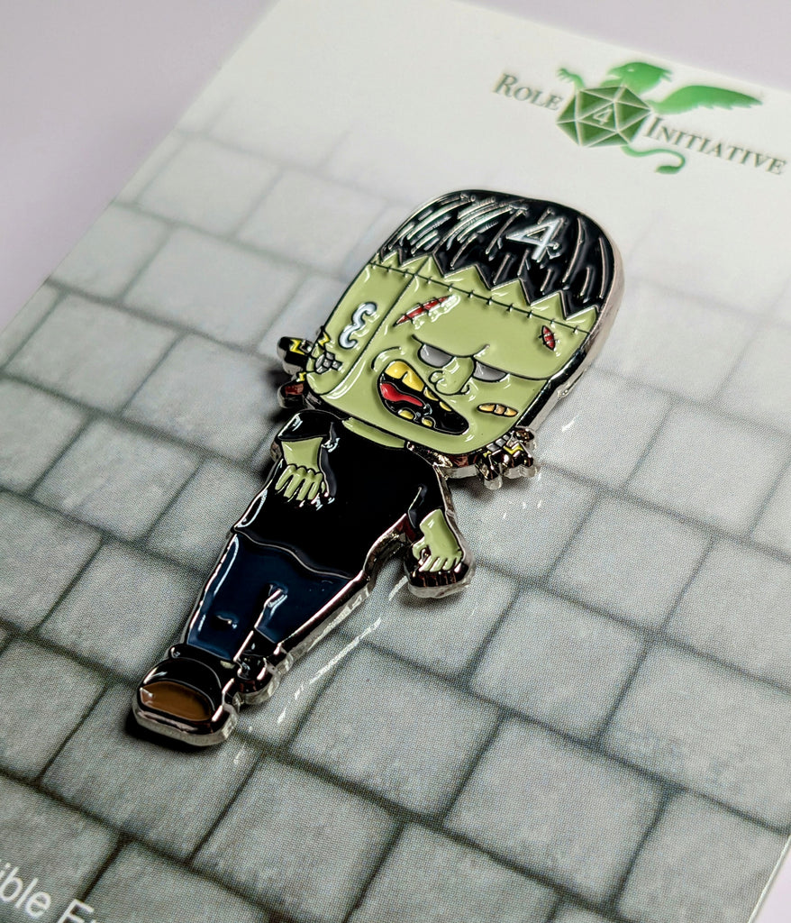 A collectible enamel pin featuring a stylized, cartoonish character with a black top and blue jeans, with a '4' on the top left, and a green face with black hair.