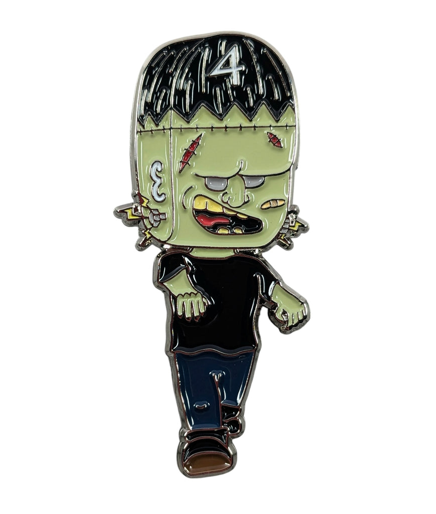 A collectible enamel pin featuring a stylized, cartoonish character with a black top and blue jeans, with a '4' on the top left, and a green face with black hair.