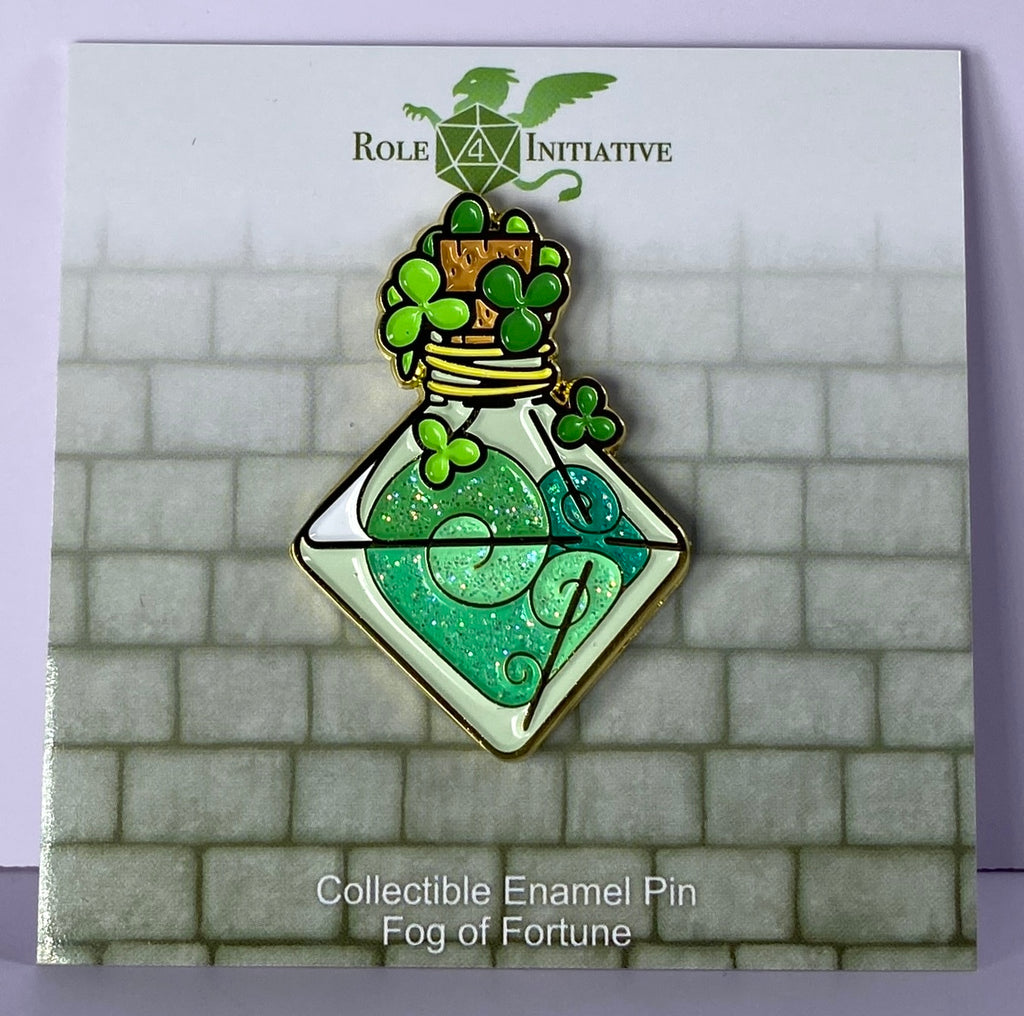 A collectible enamel pin featuring a glittering green pin with a d8-shaped fortuitous vapor bottle design and lucky clovers around it.