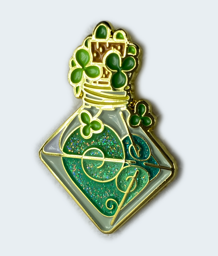 A collectible enamel pin featuring a glittering green pin with a d8-shaped fortuitous vapor bottle design and lucky clovers around it.