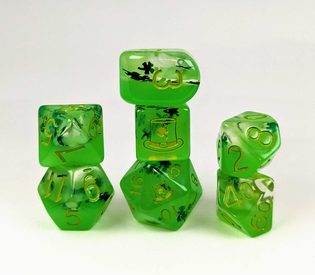 Set of layered green dice, with a solid green bottom layer that glows in the dark, and a clear top layer with diffused green and metallic dark green shamrock glitter. The dice have pale green numbers.